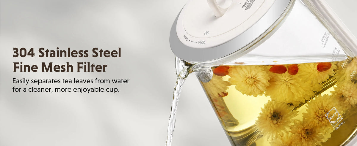 A close-up of a clear glass teapot pouring hot water, with yellow flower tea leaves visible inside. Text on the left reads '304 Stainless Steel Fine Mesh Filter' and 'Easily separates tea leaves from water for a cleaner, more enjoyable cup.