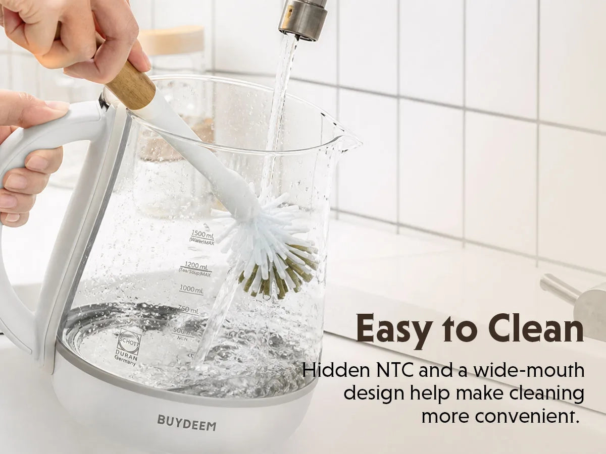 A white K123 Multi-function Beverage Maker with a wide-mouth brush inside, being rinsed with running water from a faucet. A hand holds the brush handle.