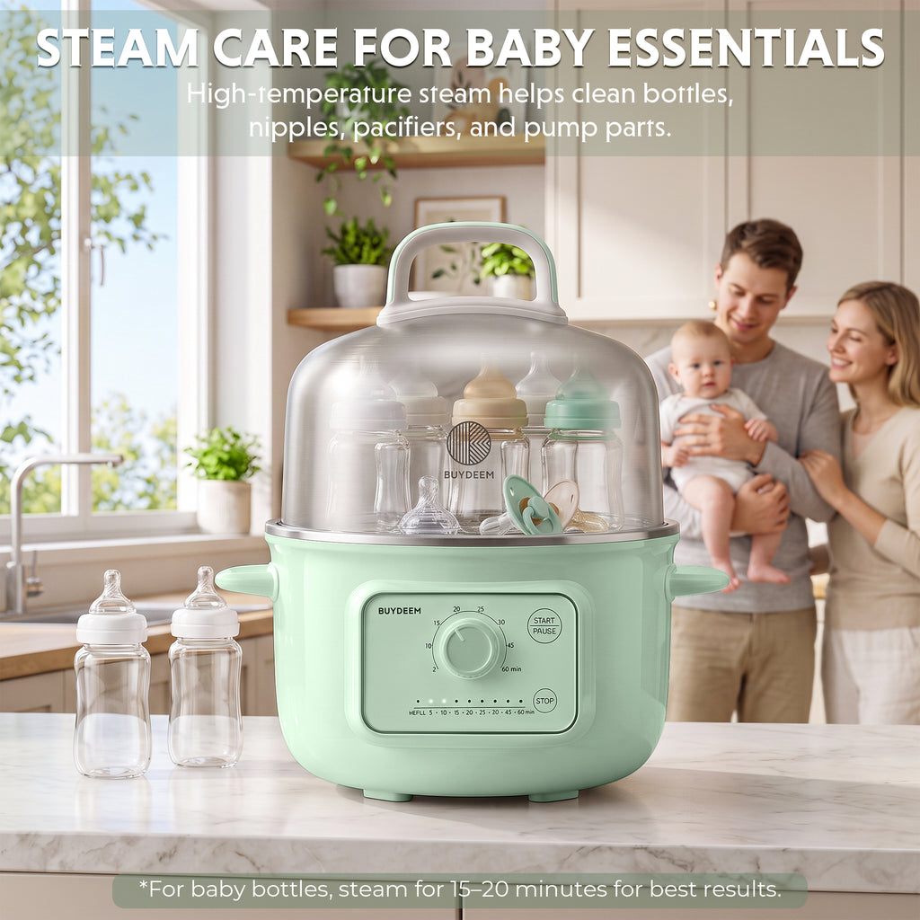 A mint green BUYDEEM steamer sits on a kitchen counter in a bright kitchen, with baby bottles inside and outside the steamer. A blurred family is visible in the background, and text at the top reads 'STEAM CARE FOR BABY ESSENTIALS'.